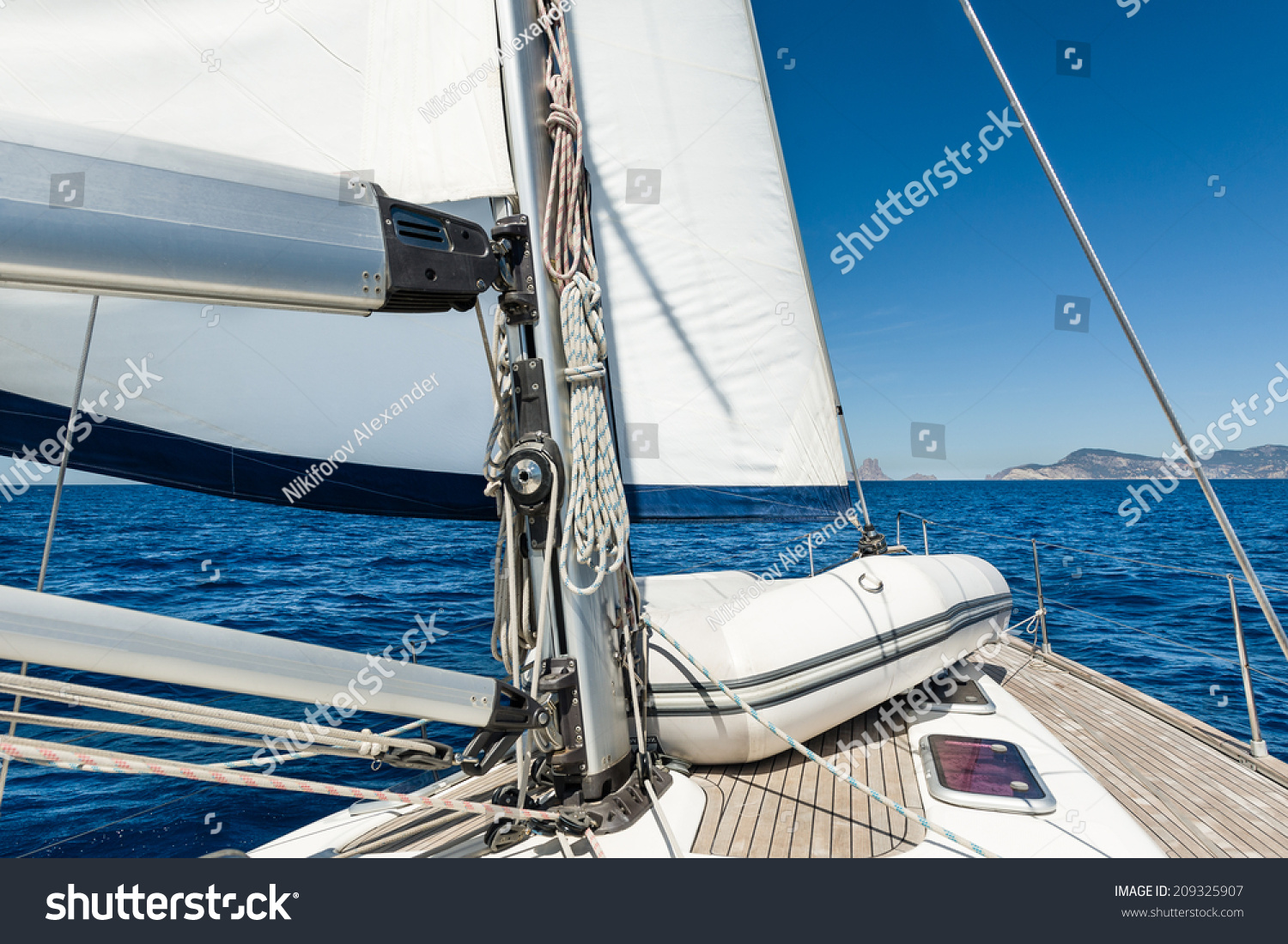 stock-photo-sailing-yacht-going-on-her-sails-in-calm-weather-with-dinghy-on-board-209325907